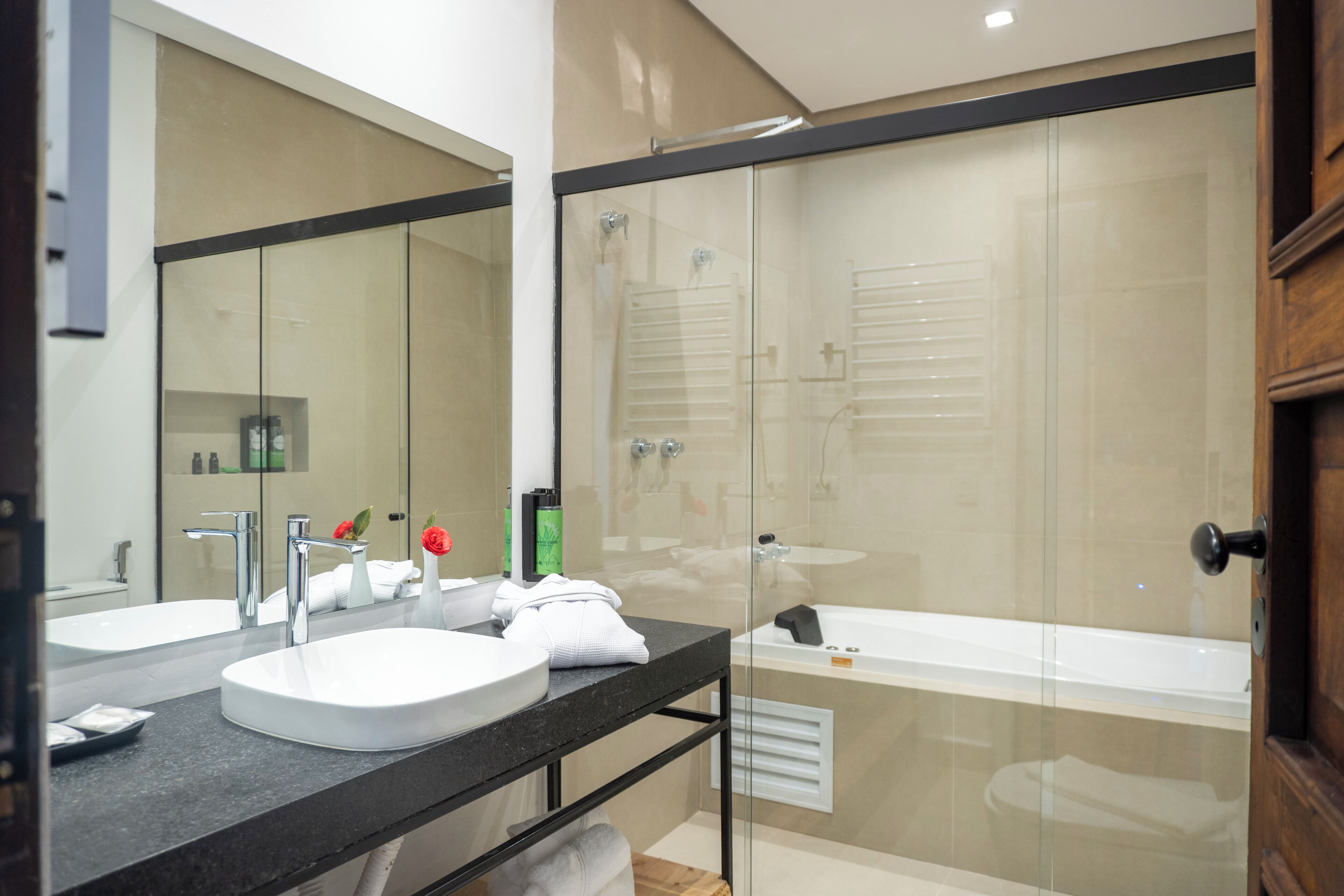 A modern bathroom with a glass-enclosed shower, a double sink vanity, and a bathtub.