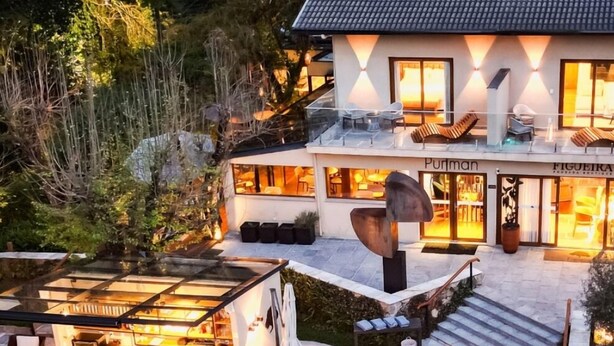 Ein modernes Haus mit Swimmingpool, Sitzgelegenheiten im Freien und einem Restaurant.