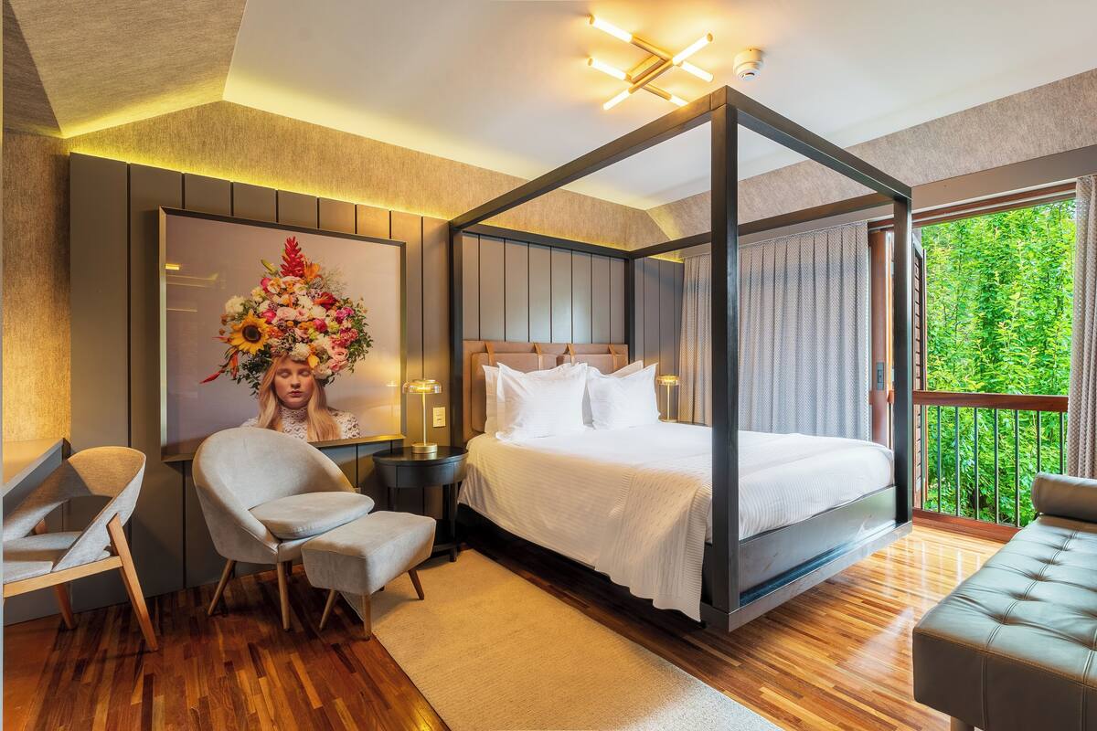 Camera da letto moderna con letto a baldacchino, una scrivania, una sedia e vista sul verde.