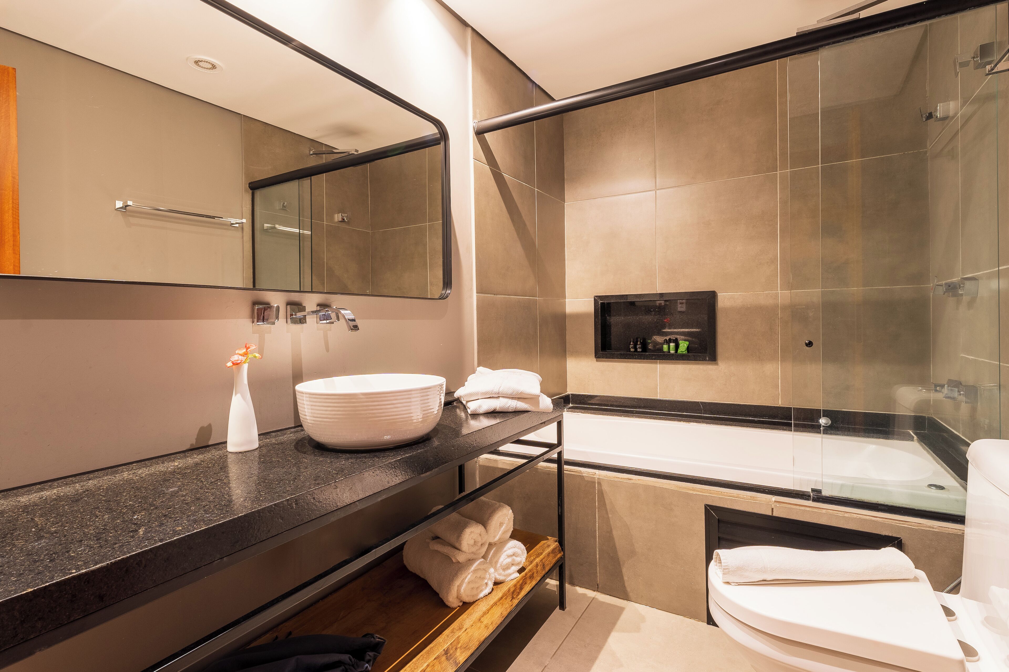 A modern bathroom with a large mirror, a sink, a bathtub, and a shower area.