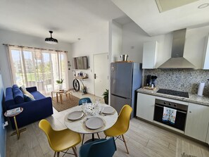 Eine moderne Wohnung mit Essbereich, Küche, Wohnzimmer und großen Fenstern.