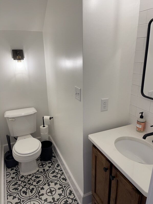 A bathroom with a toilet, a sink, and a mirror. - 315 West 14th Street (Owensboro)