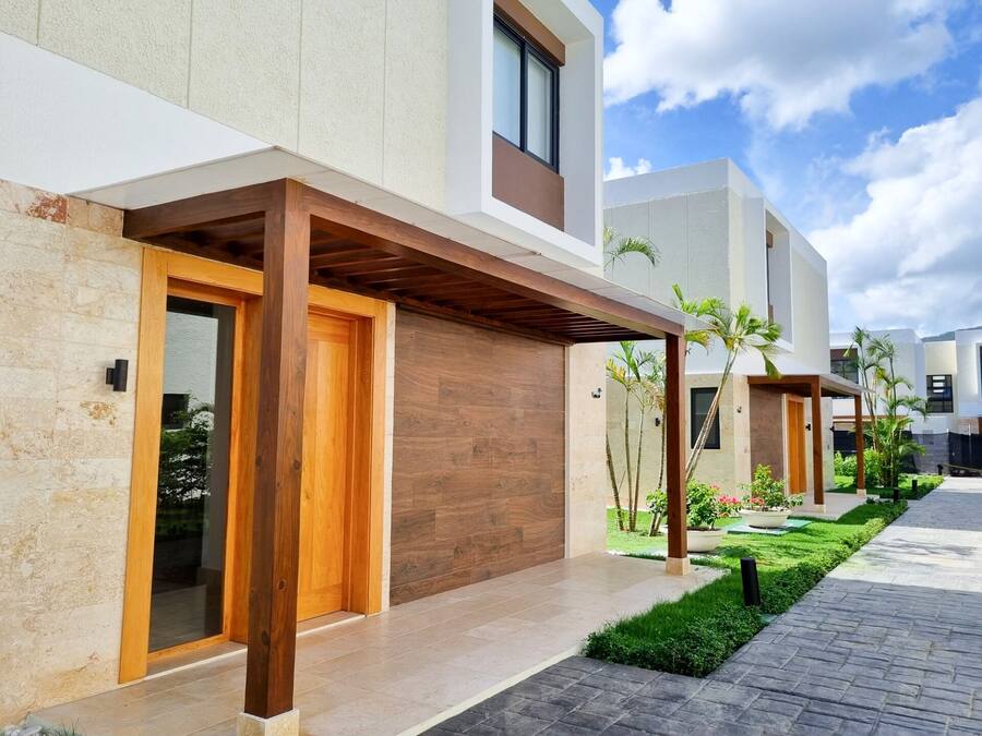 A modern residential building with a wooden entrance, tiled pathway, and a well-maintained garden.