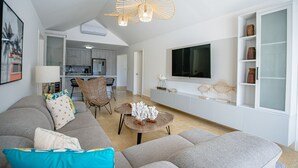 Een moderne woonkamer met een grijze bank, een salontafel en een eethoek met stoelen.