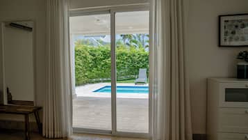 Una habitación con puerta de vidrio corredera que da a una zona de piscina, un banco y un armario.