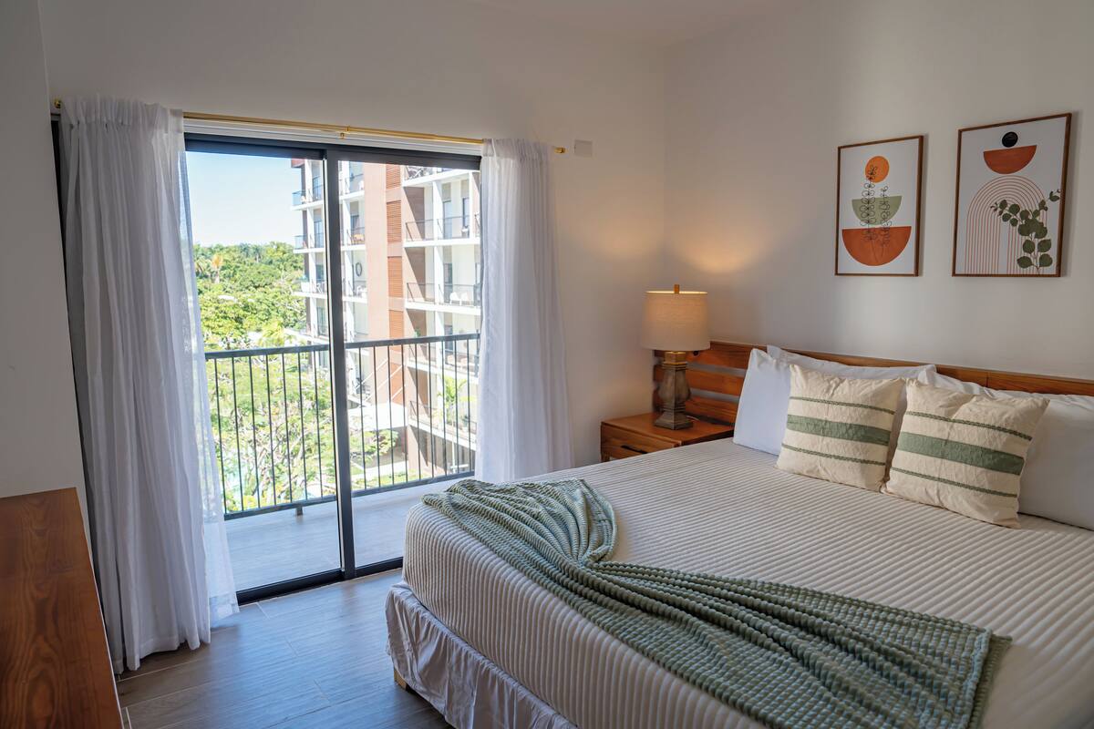 Une chambre d’hôtel avec un grand lit, une table de chevet, une lampe et deux œuvres d’art murales.