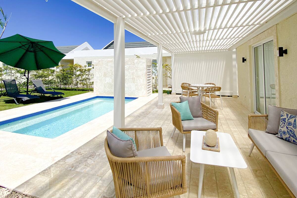Un espace extérieur abrité comprenant une piscine, des chaises longues et des coins salon.