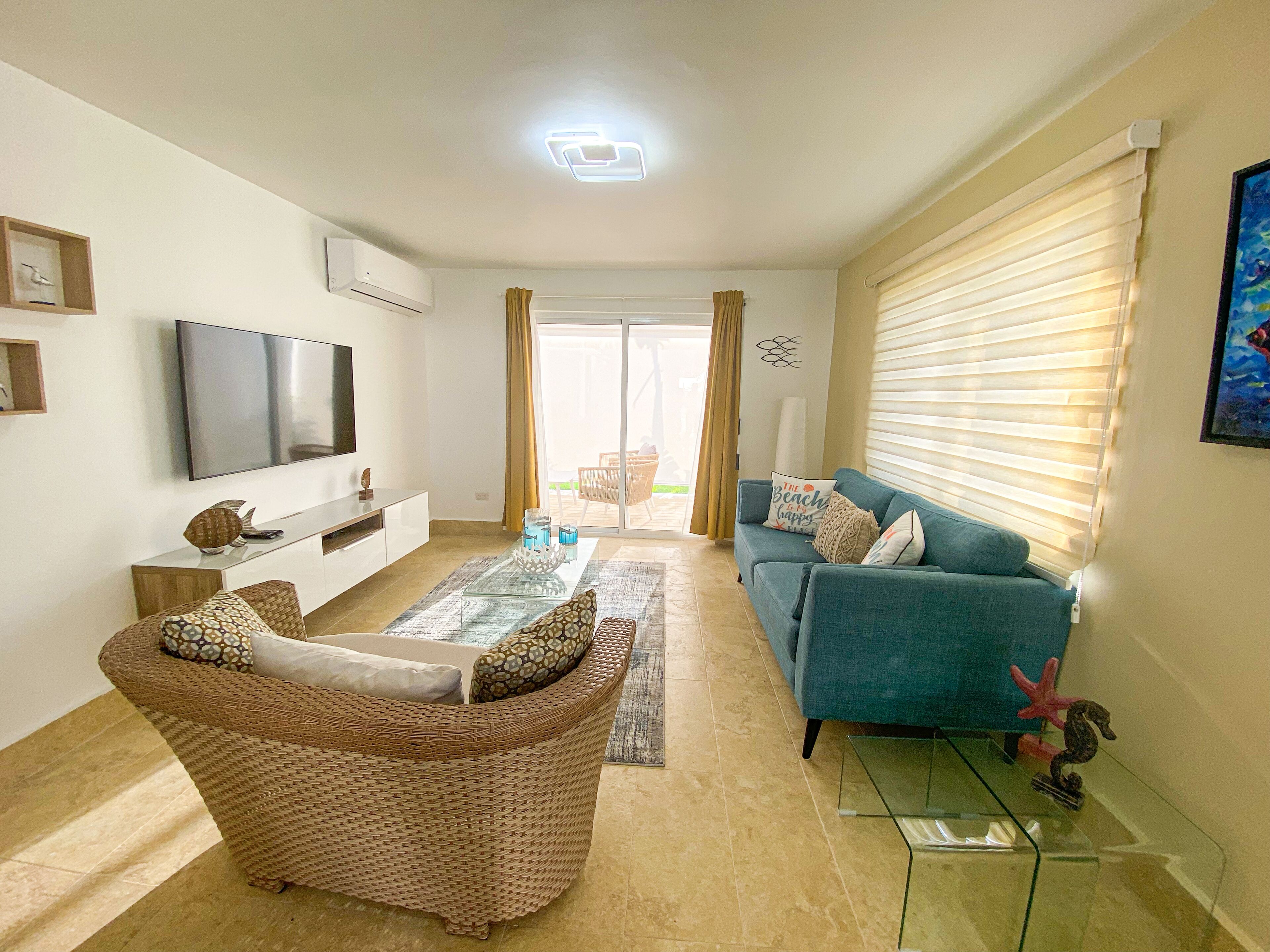 A living room with a television, sofa, and wicker chair.