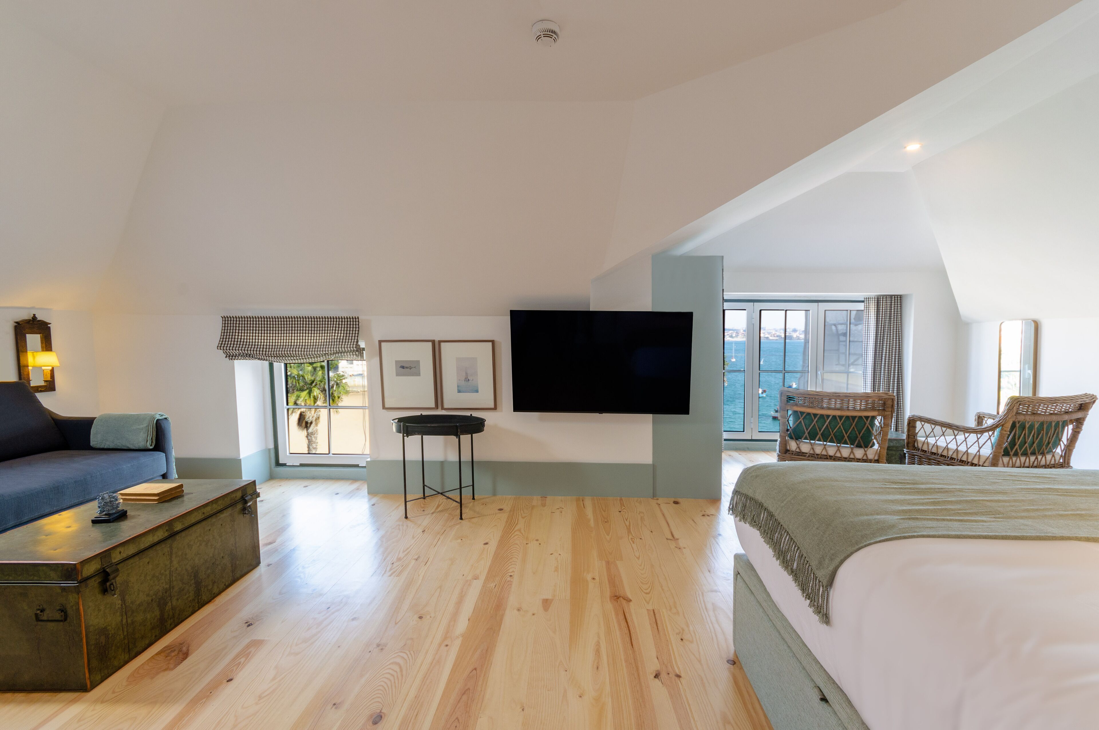 A spacious bedroom with a large bed, a flat-screen TV, a sofa, and a dining table.