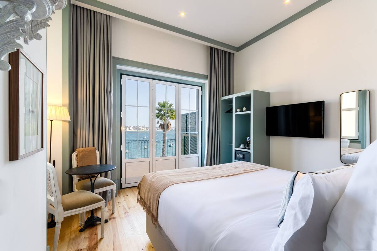 A hotel room with a bed, a desk, a chair, a TV, and a wardrobe.