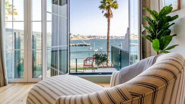 A balcony with a view of the sea, a palm tree, and a chair. - Westlight Cascais Chalet - Adults Only. (Cascais)