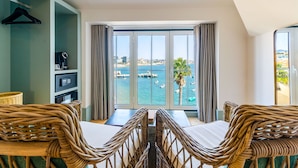 A balcony with wicker furniture, a view of the sea, and a cityscape in the background. - Westlight Cascais Chalet - Adults Only. (Cascais)
