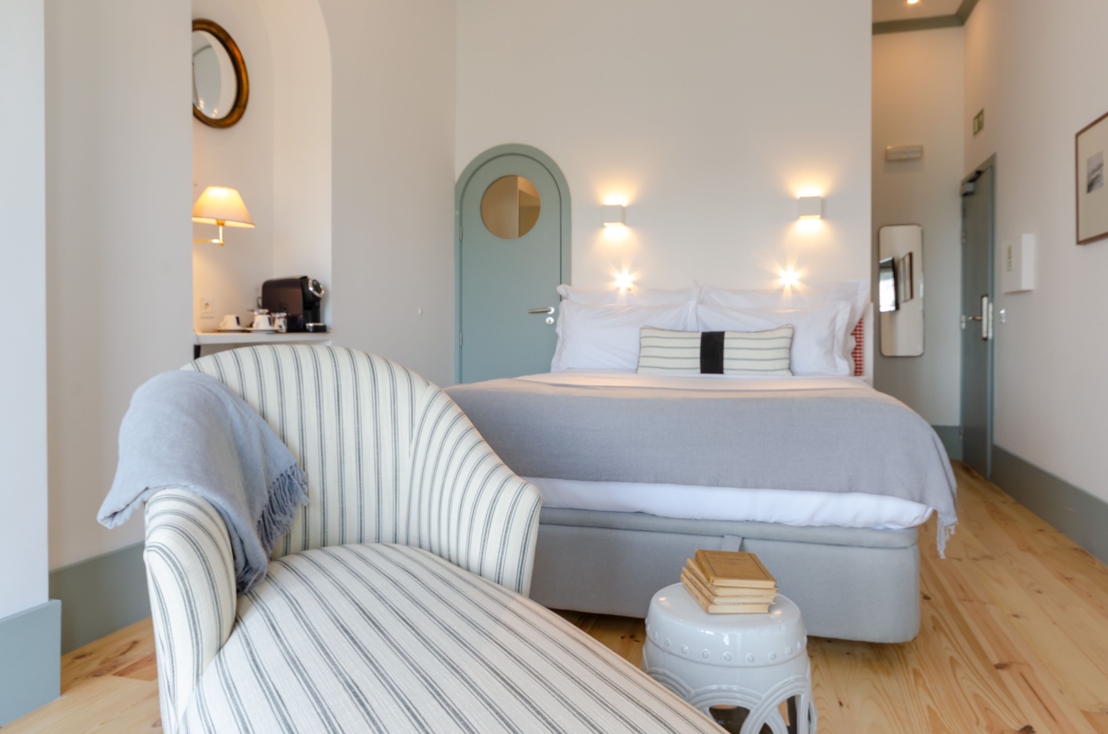 A bedroom with a bed, a bedside table, a chair, and a small stool.