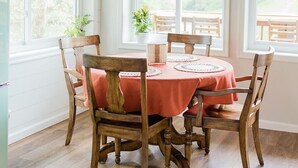 A dining area with a round table, wooden chairs, and a woven pendant light. - THE NEST ~ Charming  cabin escape ~ Hot tub ~ Suana ~ Bbq (Lenhartsville)