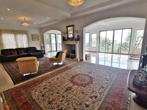A spacious living room with a large rug, a sofa, a chair, and a fireplace.