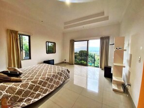 A spacious bedroom with a large bed, a wardrobe, and a view of the outdoors.