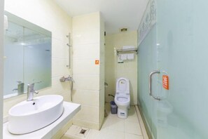 A bathroom with a white sink, a toilet, and a glass shower enclosure.