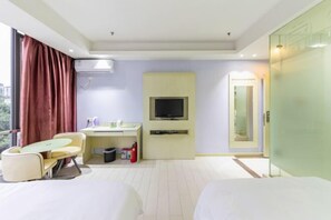 A hotel room with a bed, a desk with a chair, a television, and a window with curtains.