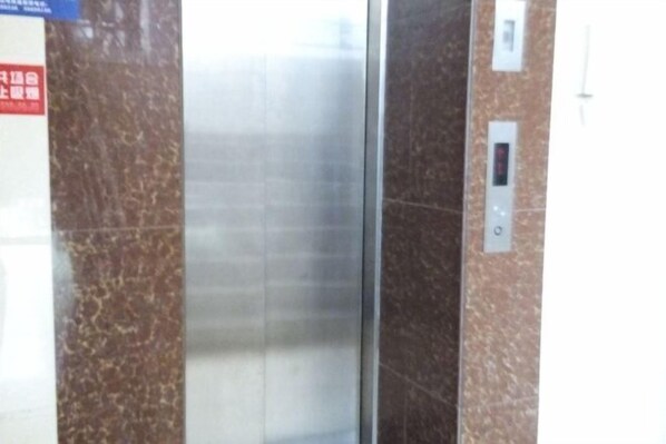 An elevator with metallic walls and a control panel on the right.