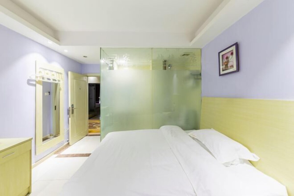 A bedroom with a bed, a wardrobe, and a glass-enclosed shower area.