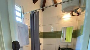 Et lille badeværelse med toilet, brusebad og håndvask.