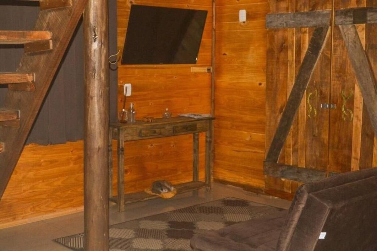 Une pièce rustique avec des murs en bois, un escalier en bois, une petite table avec un miroir et une fenêtre.
