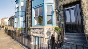 A stone building with blue window frames and a black door. - The Haven (Windermere)