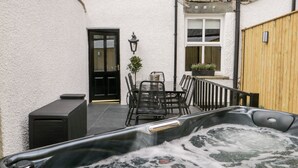 A hot tub with a stone wall and a wooden fence in the background. - The Haven (Windermere)
