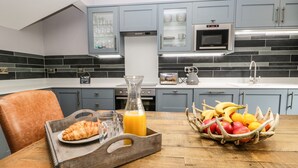 A modern kitchen with grey cabinets, a microwave, and a fruit basket on the table. - The Haven (Windermere)
