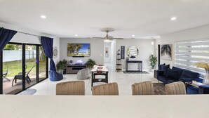 A spacious living room with a dark blue sofa, beige armchairs, a coffee table, and a ceiling fan. - Brand New Renovated COZY Home! Prime Location! Live in Style 🏡🌟⭐️💫 (Miami)