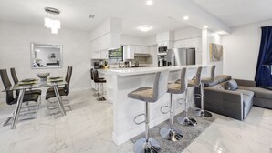A modern kitchen with white cabinets, a central island, and bar stools. - Brand New Renovated COZY Home! Prime Location! Live in Style 🏡🌟⭐️💫 (Miami)