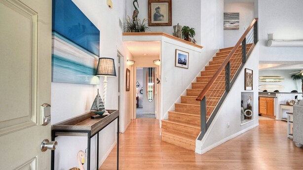 Un intérieur spacieux avec un escalier en bois, un coin repas et une vue sur l’océan.