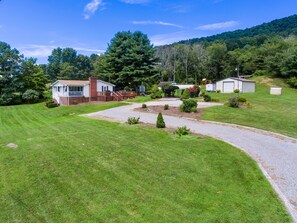 A residential property with a well-maintained lawn, a gravel driveway, and a small shed.