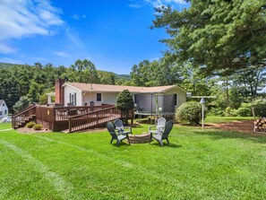 A two-story house with a deck, outdoor seating area, and a trampoline.