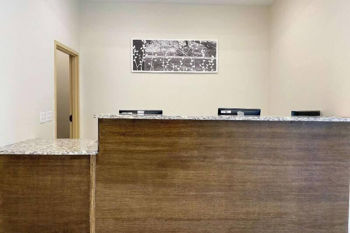 A reception desk with a wooden finish, a framed artwork above it, and a door to the left.