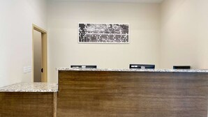 Una recepción con mostrador de madera y encimera de granito. Se observa una obra de arte enmarcada sobre el mostrador.