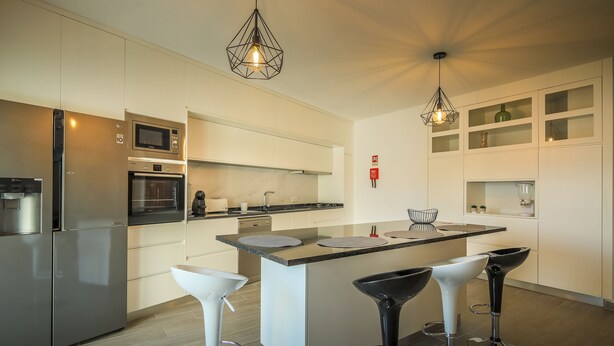 Una cocina moderna con una isla central, electrodomésticos de acero inoxidable y taburetes de bar.