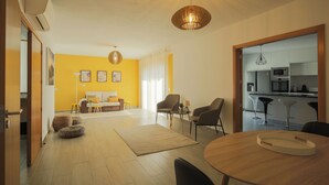 Una sala de estar moderna con un sofá, sillas, una mesa de comedor y una cocina al fondo.
