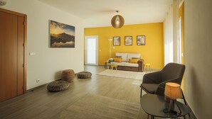 Una sala de estar moderna con un sofá, una butaca, una lámpara y un cuadro en la pared.