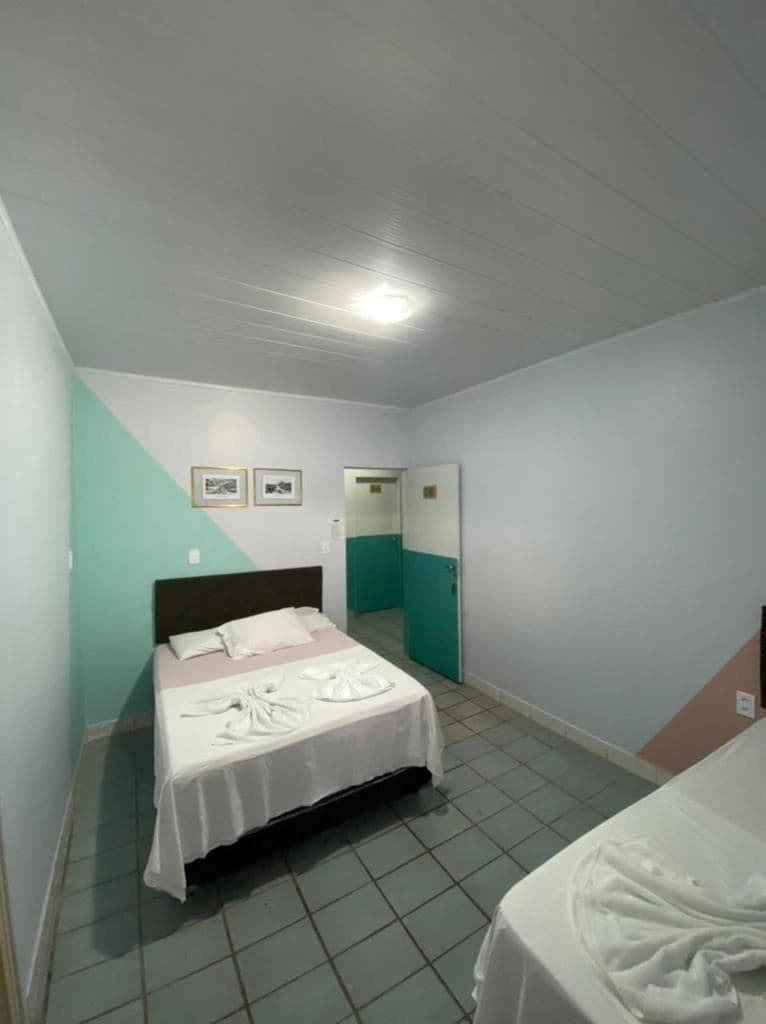 A bedroom with a bed, a bedside table, and a door leading to another room.