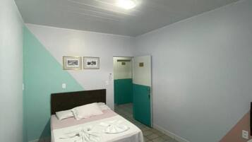 A bedroom with a bed, a bedside table, and a door leading to another room.