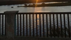 A sunset over a body of water with a distant power line tower. - Pousada Vila do Penedo (Penedo)