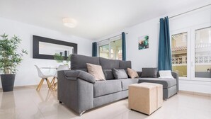 Un salón moderno con un sofá gris, una mesita y una planta en maceta.