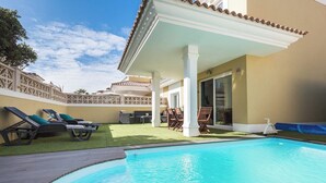 Una piscina con sillas de descanso y un área de patio techada.