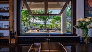 A kitchen with a large window overlooking a garden and a view of the sea. - Stunning Luxury Villa/ Private Infinity Pool with Panoramic Sea Views (Sint Willibrordus)