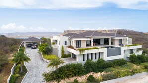 A modern two-story house with a swimming pool, a covered carport, and a view of the surrounding landscape. - Stunning Luxury Villa/ Private Infinity Pool with Panoramic Sea Views (Sint Willibrordus)
