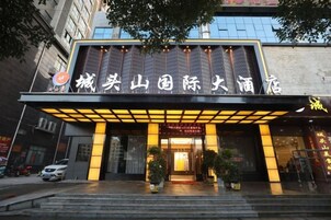 A hotel entrance with a large sign, steps leading up to it, and potted plants.