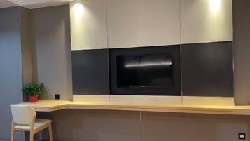 Ein modernes Wohnzimmer mit integriertem Fernseher, einem Holztisch und einem Sessel.