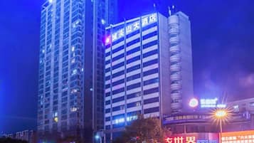 Un hotel moderno de gran altura con varios pisos, señalización iluminada y una entrada destacada.
