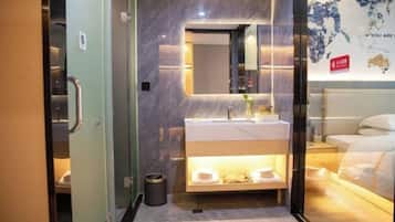 Een moderne hotelkamer met een glazen scheidingswand, een betegelde marmeren muur, een groot bed, een nachtkastje en een spiegel aan de muur.